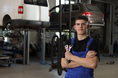 Young auto mechanic with wrenches at automobile repair shop