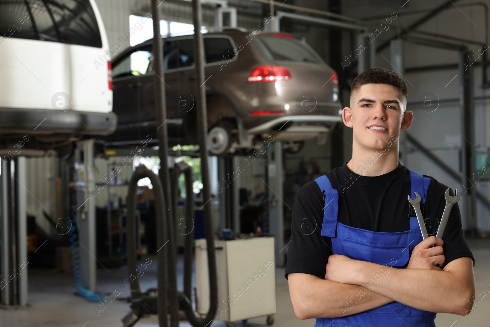 Photo of Young auto mechanic with wrenches at automobile repair shop