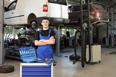 Young auto mechanic with different tools at automobile repair shop