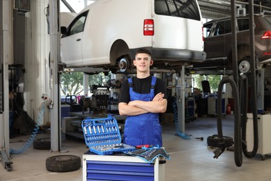 Photo of Young auto mechanic with different tools at automobile repair shop