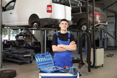 Photo of Young auto mechanic with different tools at automobile repair shop