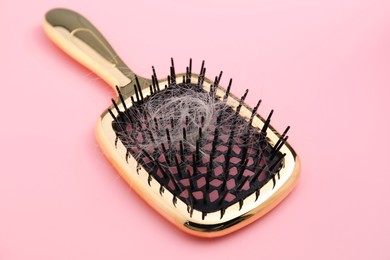 Photo of Brush with lost hair on pink background