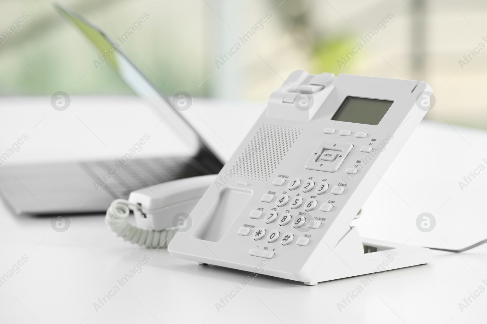 Photo of White telephone on table against blurred background