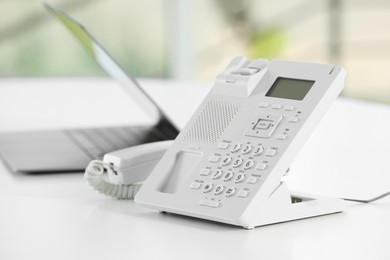 Photo of White telephone on table against blurred background