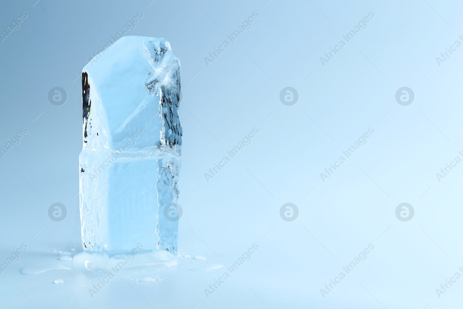 Photo of Blocks of clear ice on light blue background, space for text