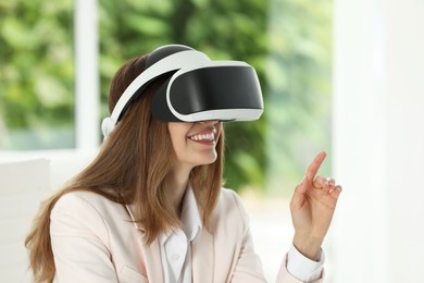Photo of Smiling woman using virtual reality headset indoors