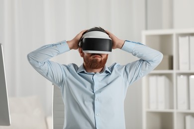Photo of Man using virtual reality headset at workplace in office