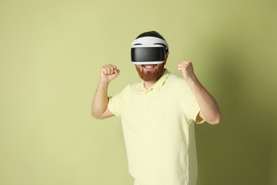 Photo of Smiling man using virtual reality headset on pale green background