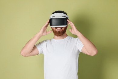 Photo of Smiling man using virtual reality headset on pale green background