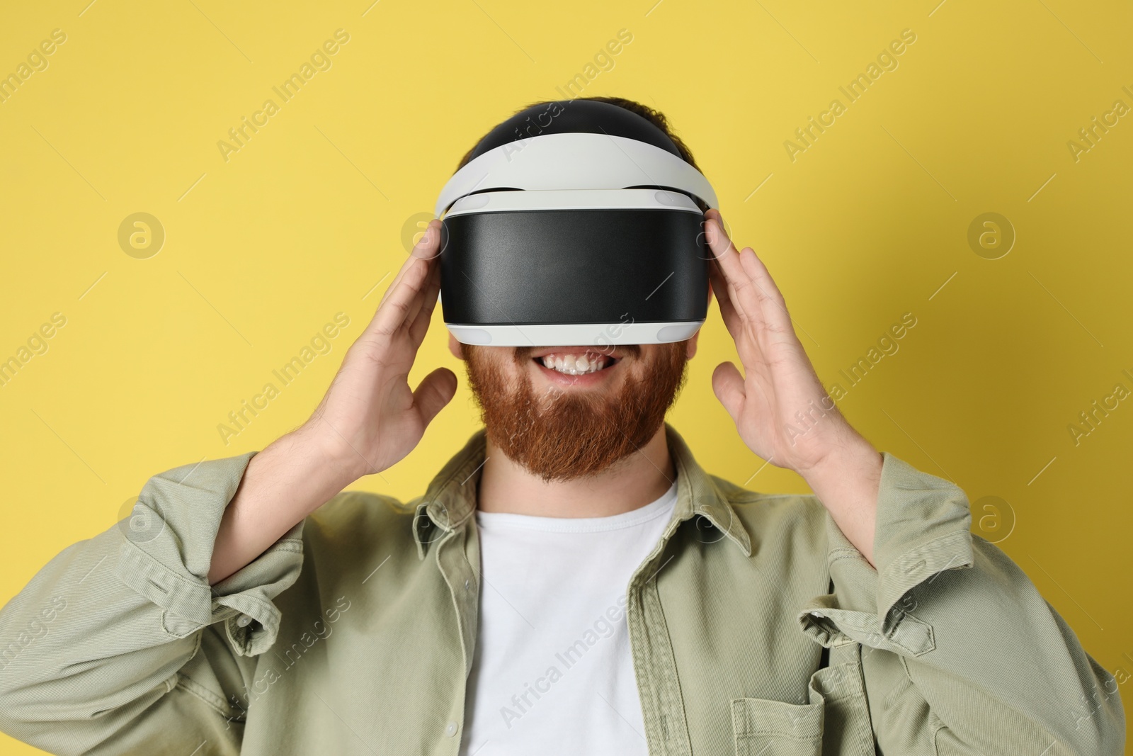 Photo of Smiling man using virtual reality headset on pale yellow background