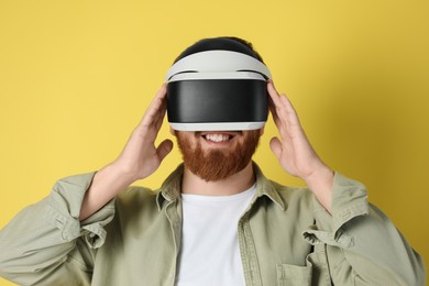 Photo of Smiling man using virtual reality headset on pale yellow background