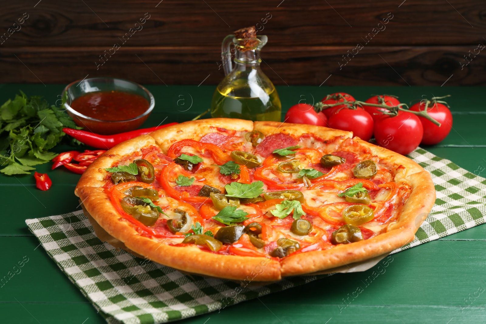 Photo of Delicious pizza Diablo and ingredients on green wooden table