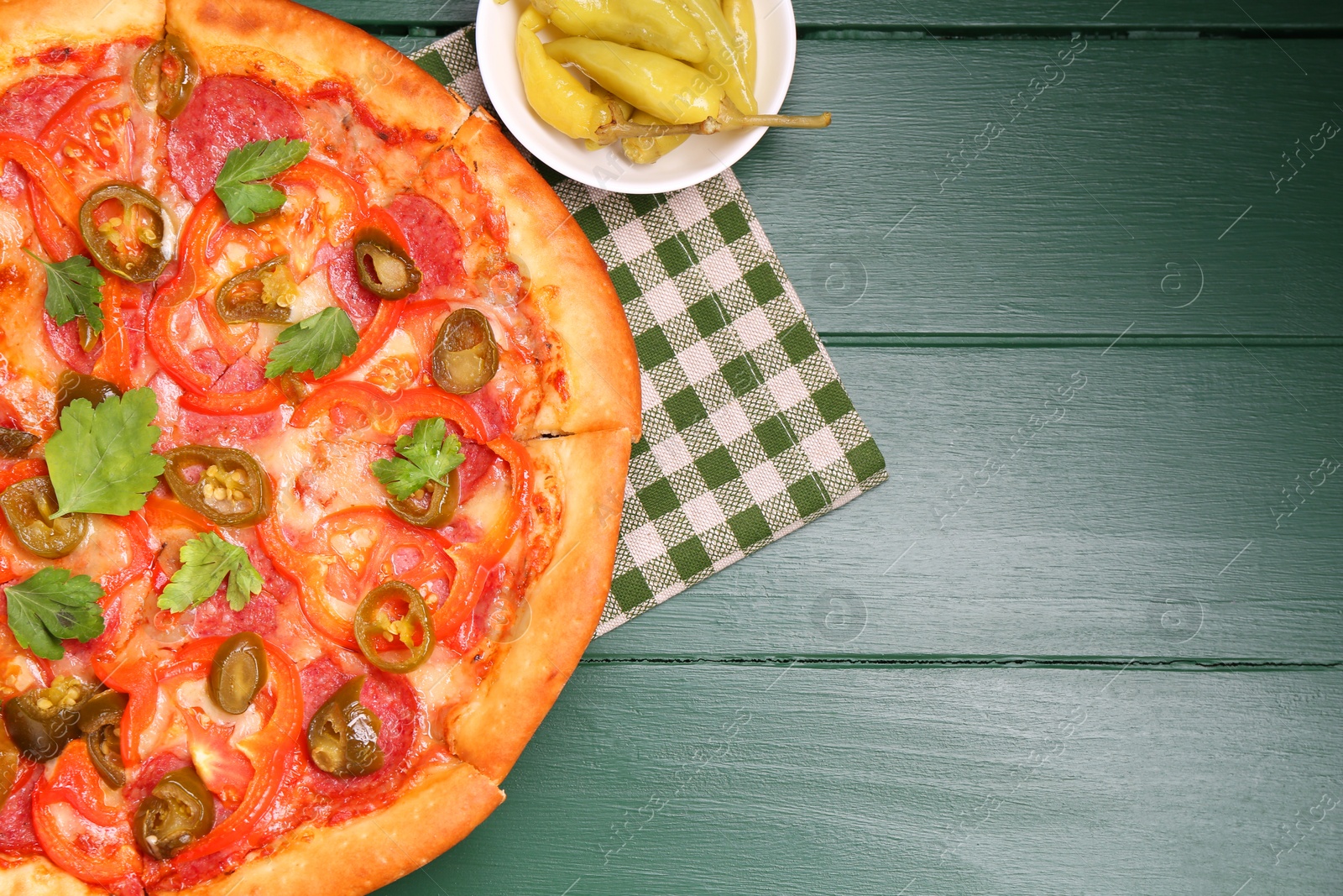 Photo of Delicious pizza Diablo and pickled peppers on green wooden table, flat lay. Space for text