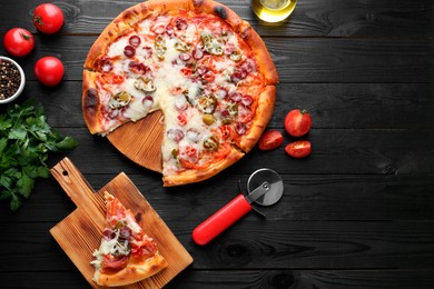 Delicious pizza Diablo, products and cutter on black wooden table, flat lay. Space for text