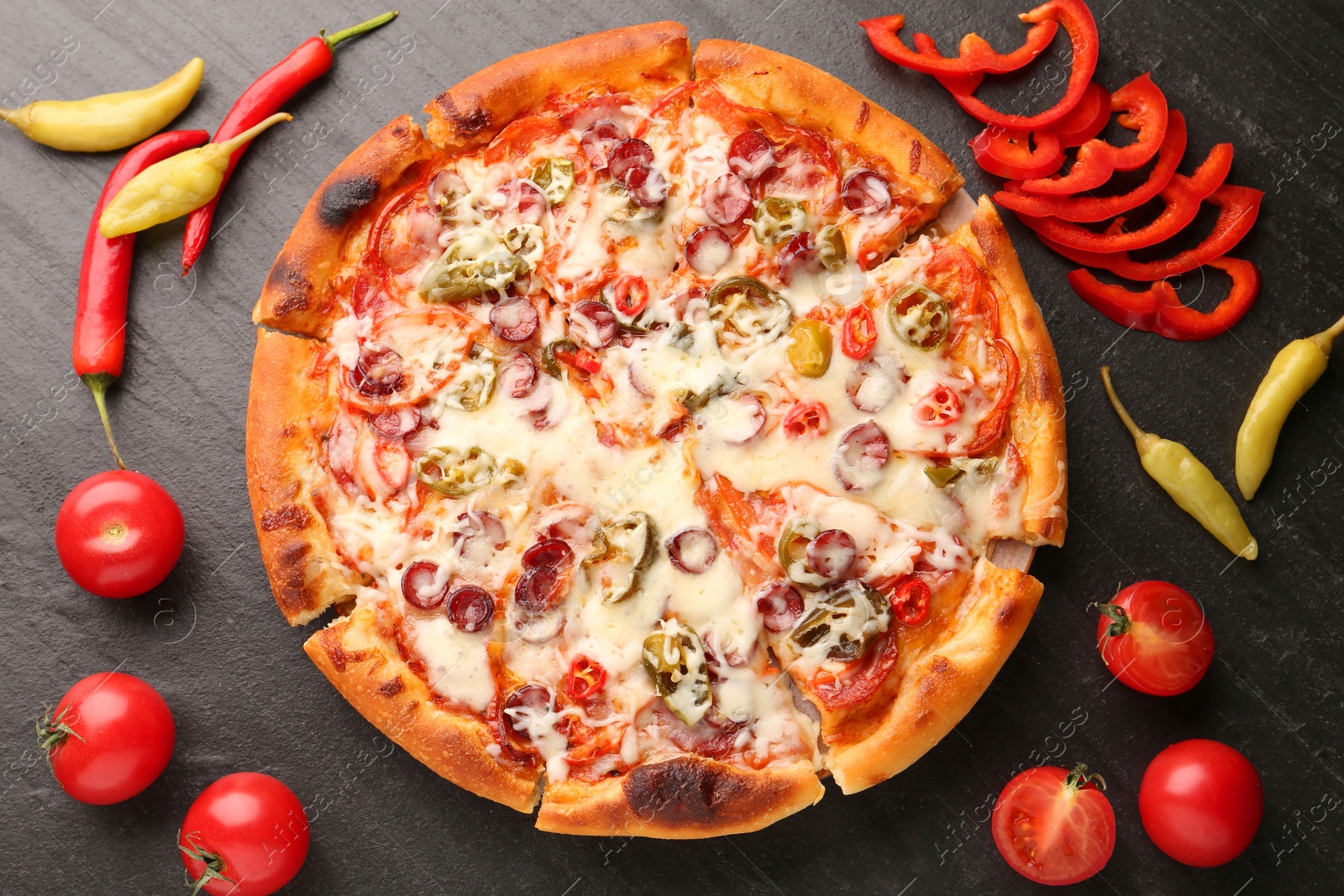 Photo of Delicious pizza Diablo among products on dark textured table, flat lay