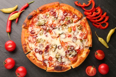 Photo of Delicious pizza Diablo among products on dark textured table, flat lay