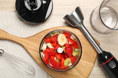 Hand blender kit with fresh fruits and strawberries on wooden table, flat lay