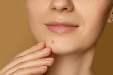 Photo of Woman with mole on her skin against beige background, closeup