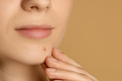 Photo of Woman with mole on her skin against beige background, closeup. Space for text