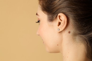 Photo of Woman with mole on her skin against beige background, closeup. Space for text