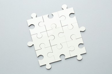 Photo of White puzzle pieces on grey background, top view