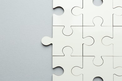 Photo of White puzzle pieces on grey background, top view. Space for text