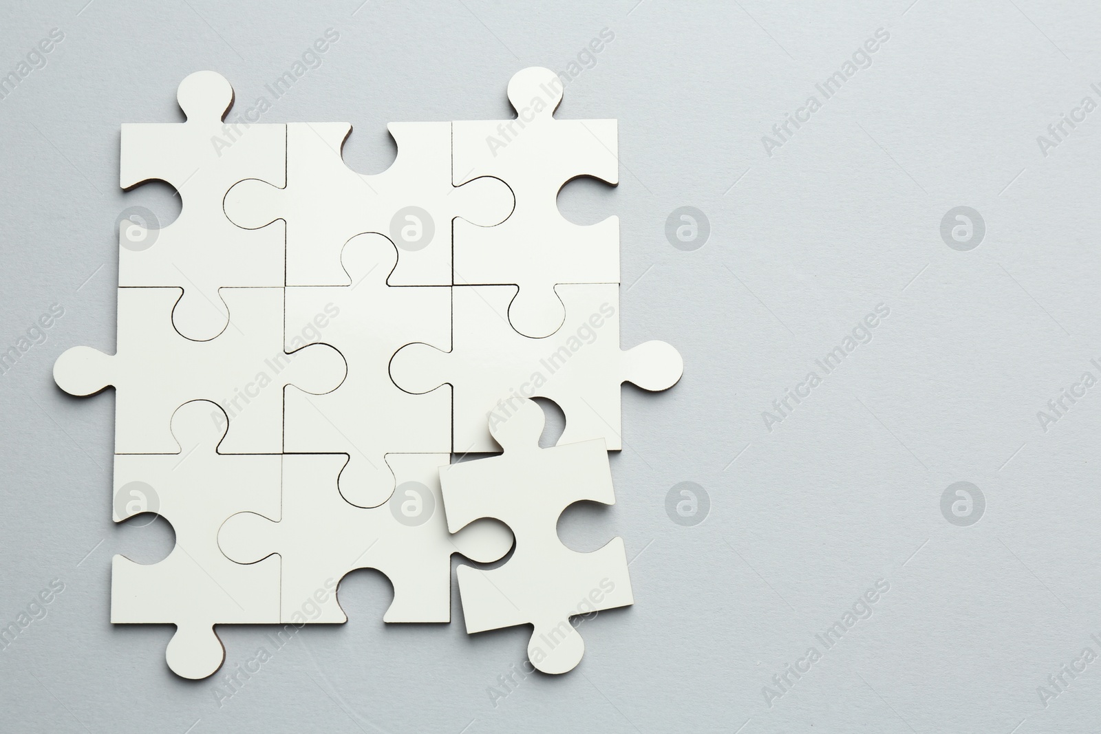 Photo of White puzzle pieces on grey background, top view. Space for text