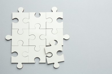 White puzzle pieces on grey background, top view. Space for text