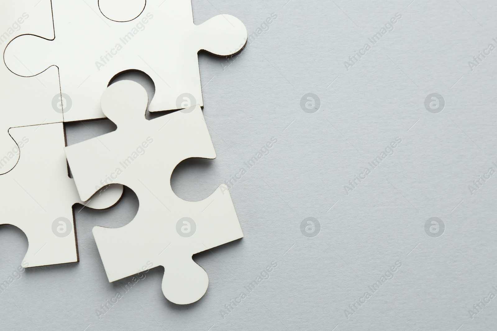 Photo of White puzzle pieces on grey background, top view. Space for text