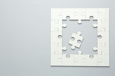 Photo of White puzzle pieces on grey background, top view. Space for text