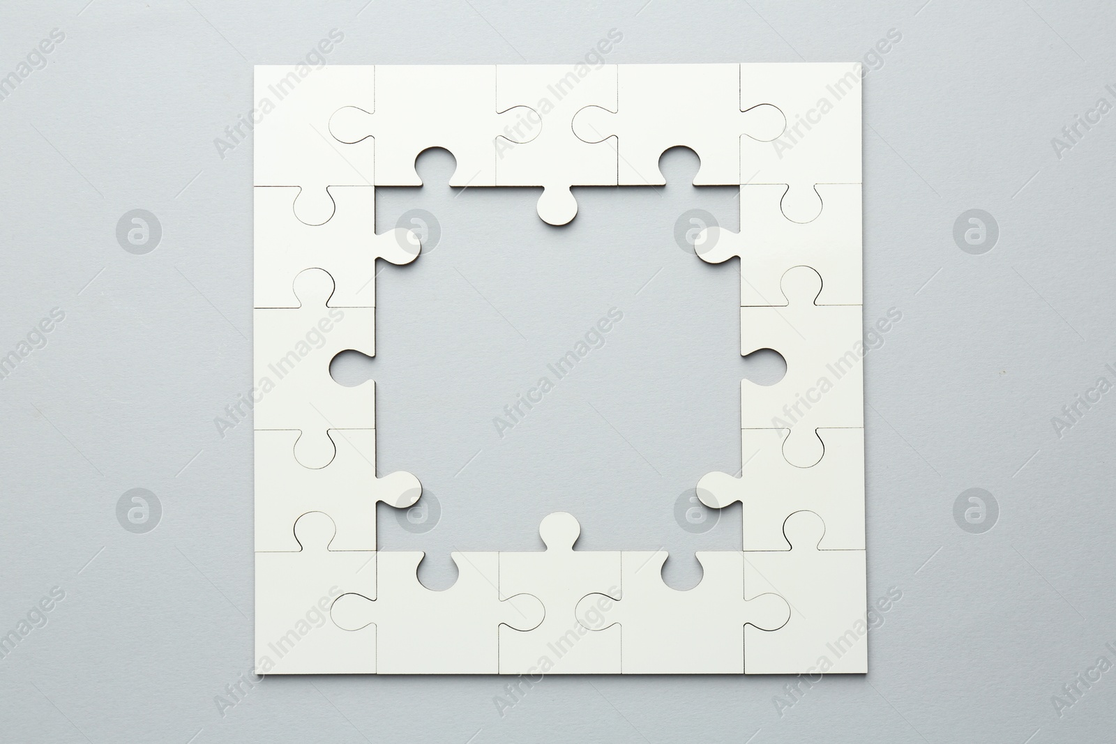 Photo of White puzzle pieces on grey background, top view