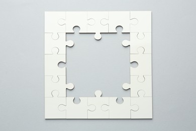 White puzzle pieces on grey background, top view