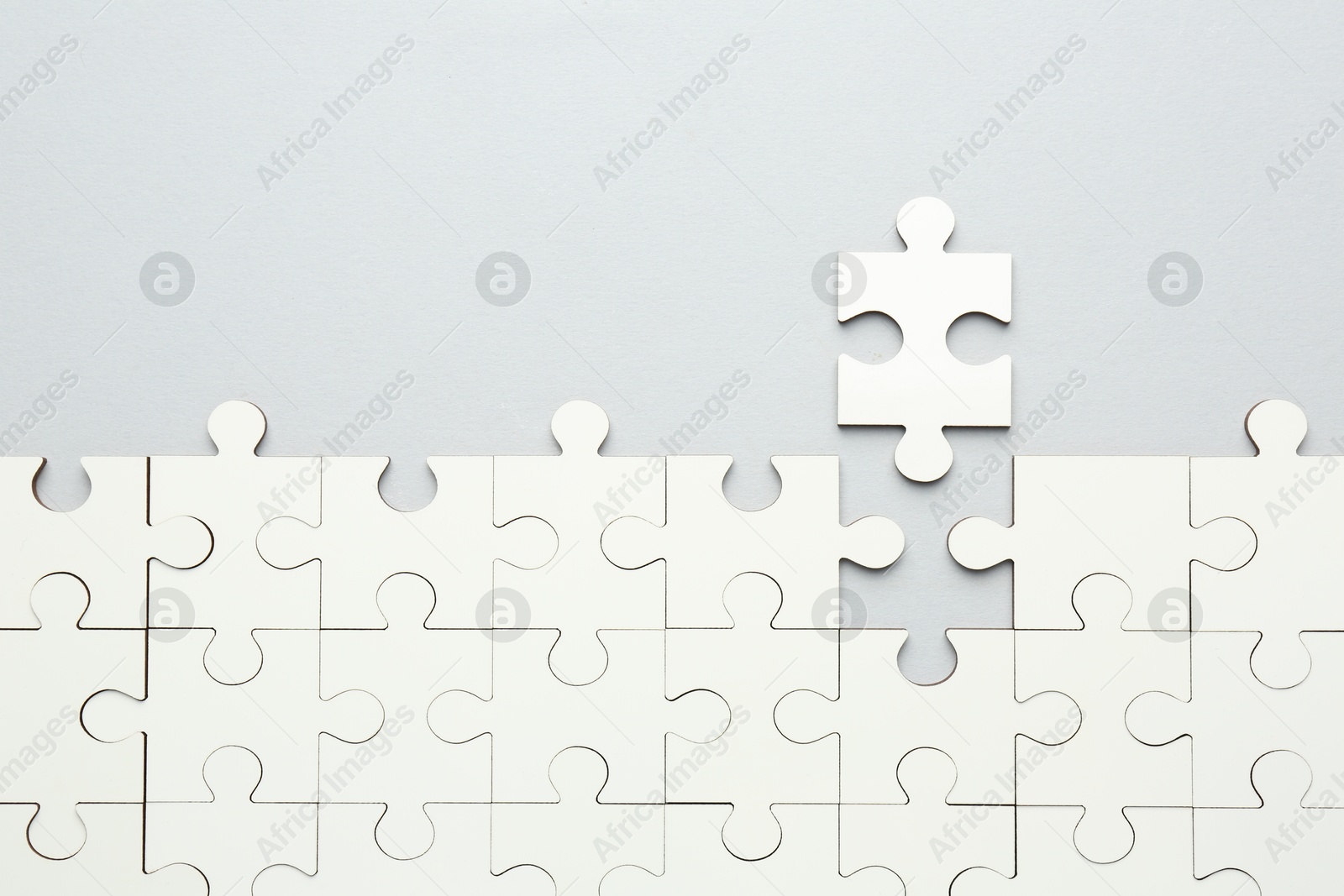 Photo of White puzzle pieces on grey background, top view. Space for text