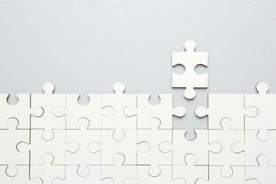 White puzzle pieces on grey background, top view. Space for text