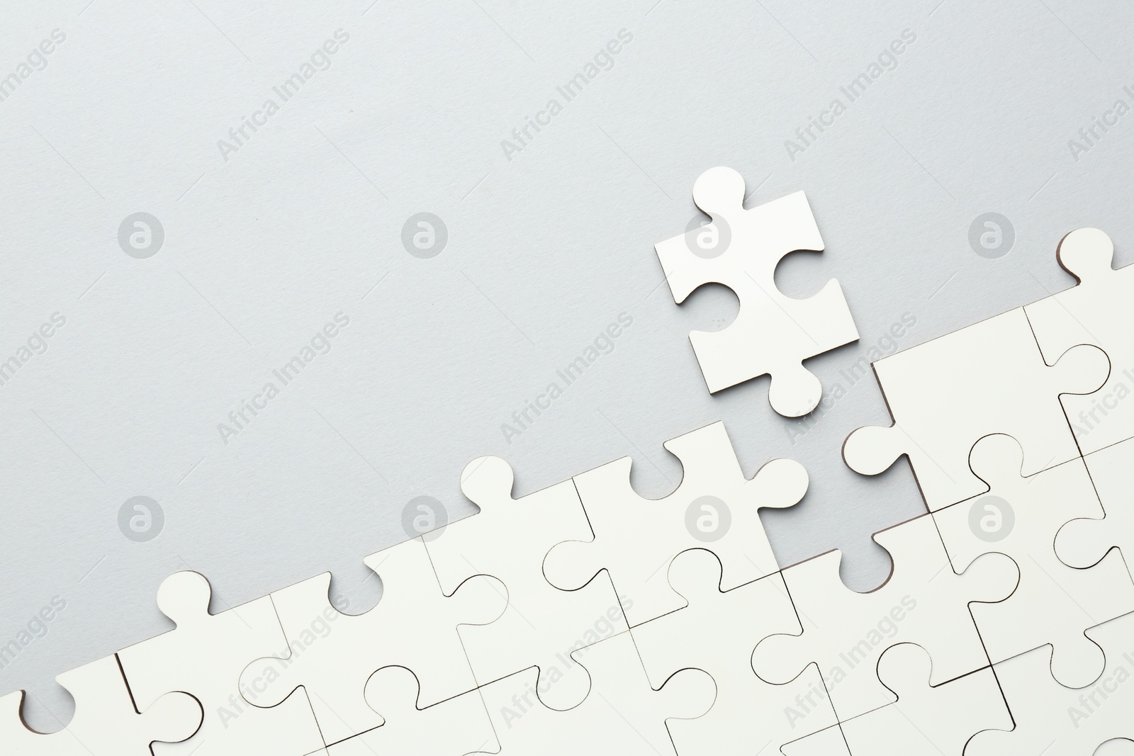 Photo of White puzzle pieces on grey background, top view. Space for text