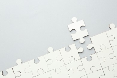 Photo of White puzzle pieces on grey background, top view. Space for text