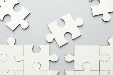 Photo of White puzzle pieces on grey background, top view