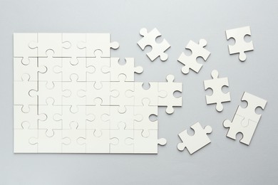 White puzzle pieces on grey background, top view