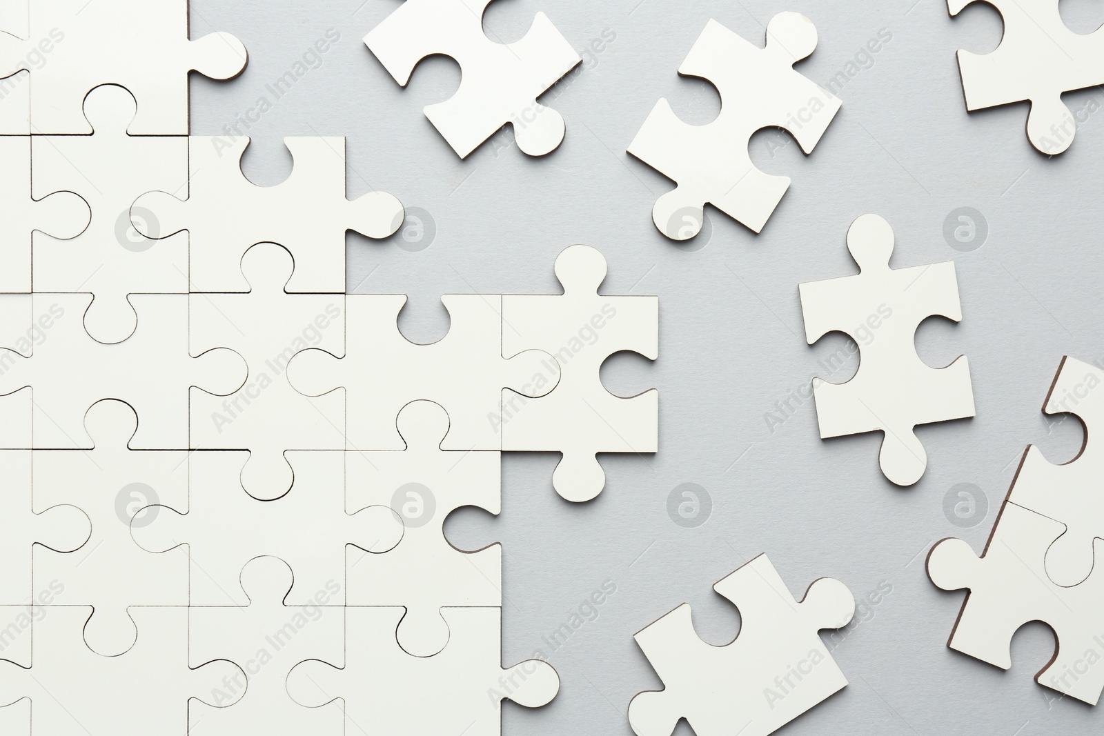 Photo of White puzzle pieces on grey background, top view