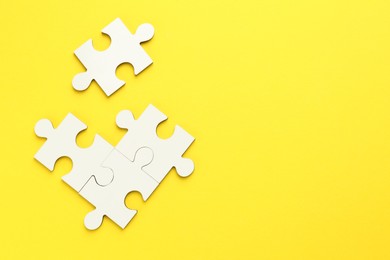 White puzzle pieces on yellow background, top view. Space for text