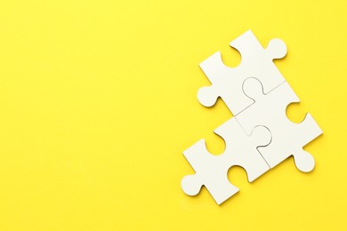 White puzzle pieces on yellow background, top view. Space for text