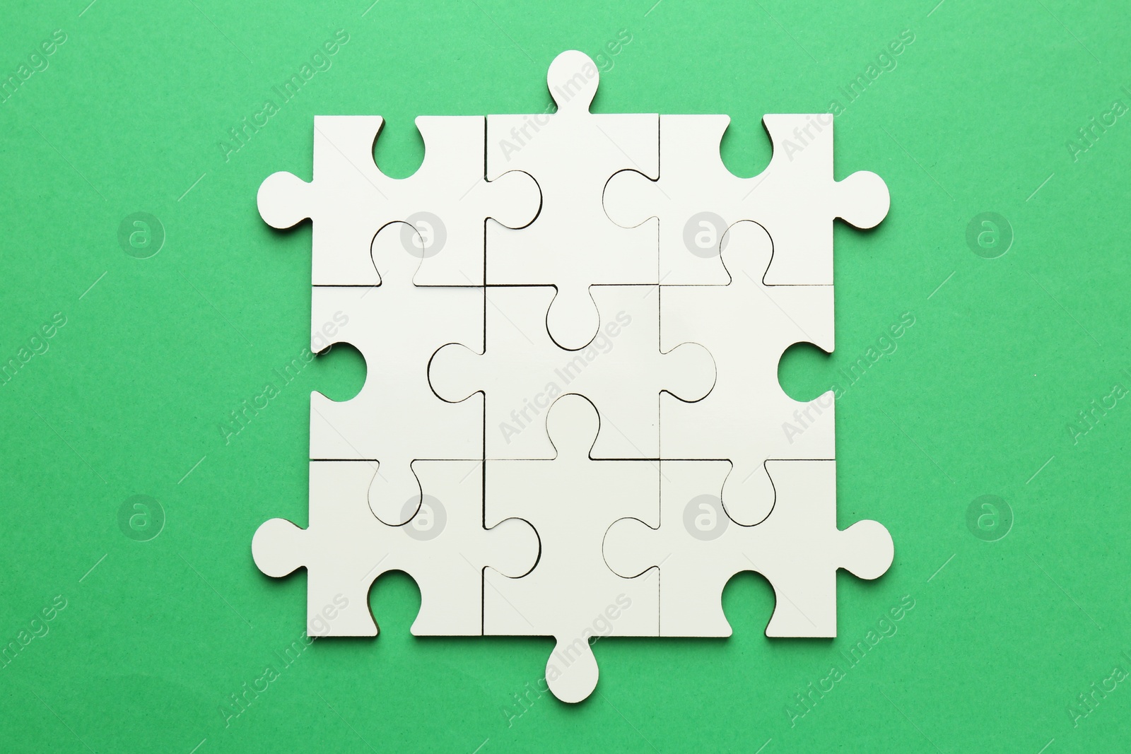 Photo of White puzzle pieces on green background, top view