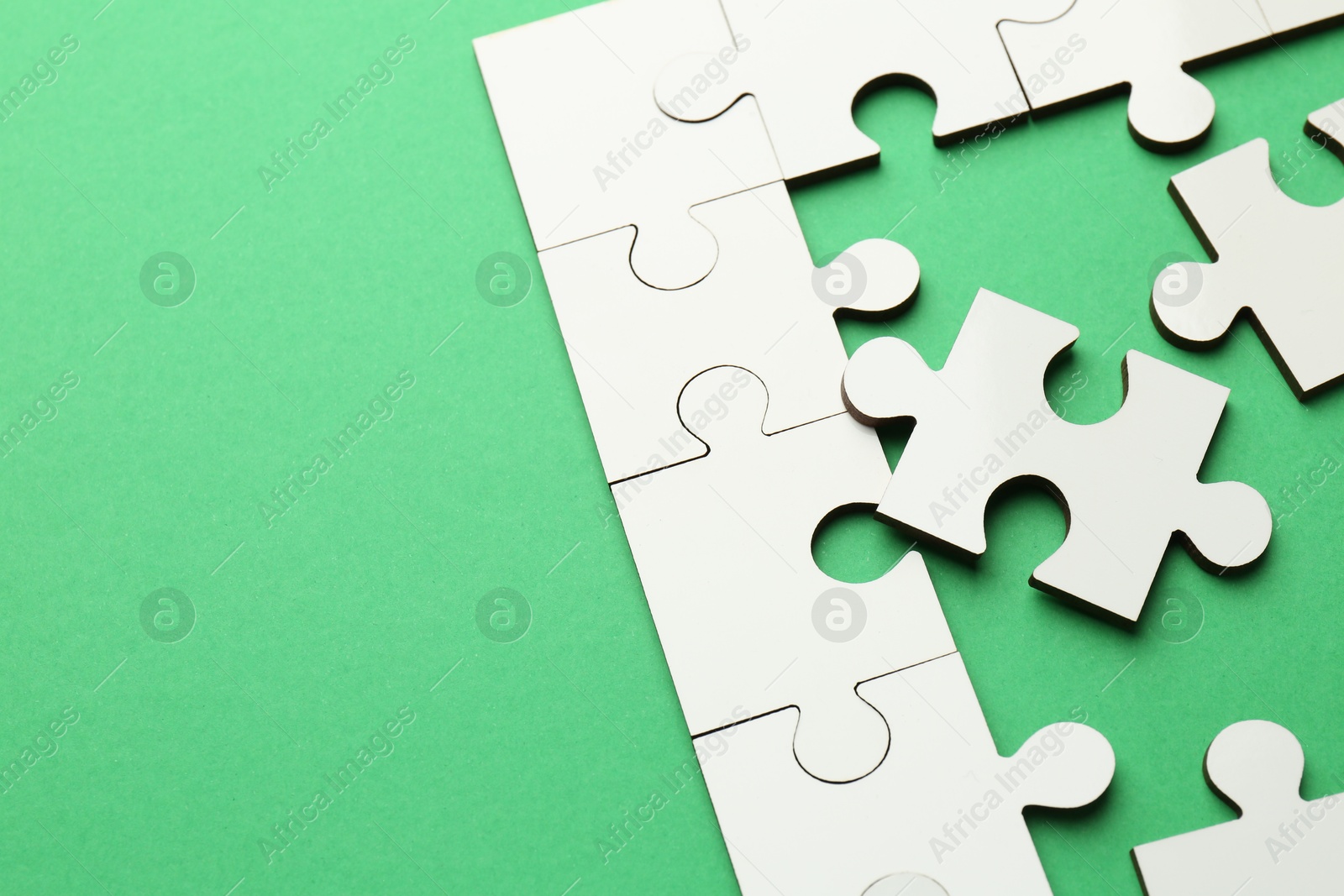 Photo of White puzzle pieces on green background, closeup