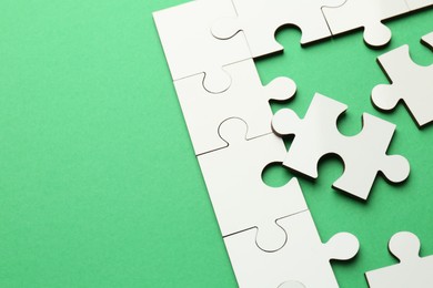 White puzzle pieces on green background, closeup