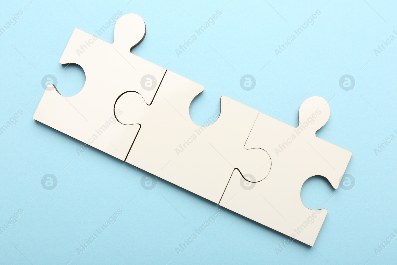 Photo of White puzzle pieces on light blue background, top view