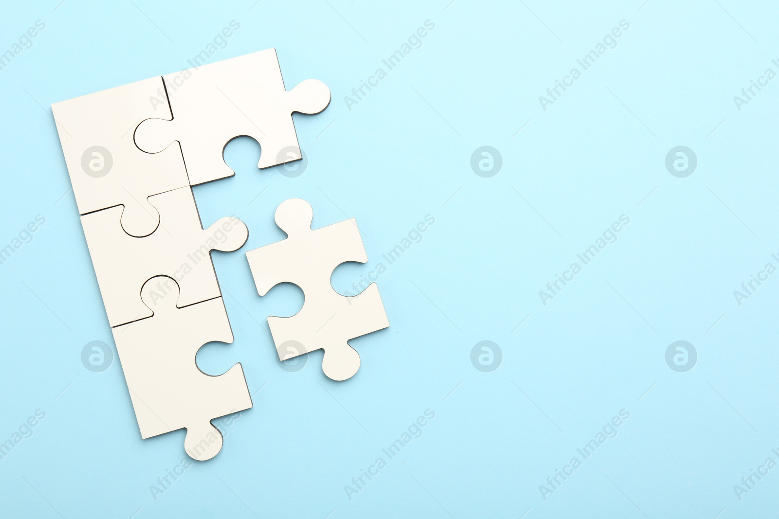 Photo of White puzzle pieces on light blue background, top view. Space for text