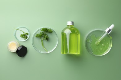 Photo of Petri dishes with cosmetic products, pipette and parsley on green background, flat lay