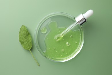 Petri dish with cosmetic product, pipette and leaf on green background, flat lay