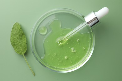 Petri dish with cosmetic product, pipette and leaf on green background, flat lay