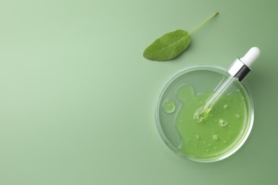 Petri dish with cosmetic product, pipette and leaf on green background, flat lay. Space for text